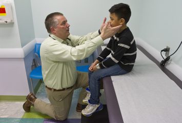 Dr. Donald Beam. medical director of the Life After Cancer Program at Cook Children's Health Care System, examines Malachi Ordonez. Photo by Mark Graham