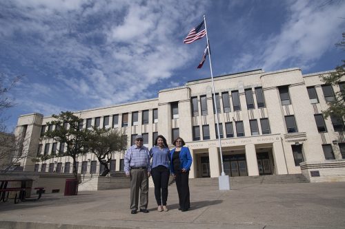 Lisa Cano (center) stands with her parents, Joe and Maria, in front of her alma mater, North Side High School, where she returns to talk with students about the Community Scholar Program. Photo by Leo Wesson