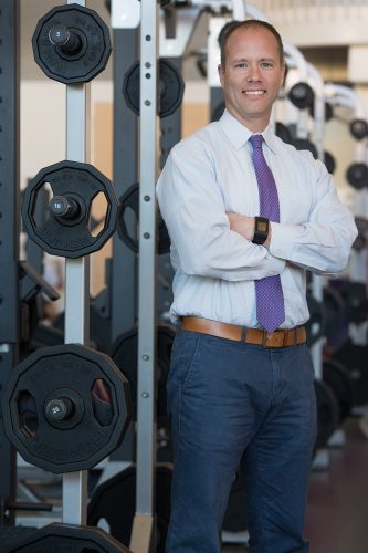 Jay Iorizzo, director of TCU's University Recreation Center, photographed at the Rec with sets of free weights in the background. Photo by Glen E. Ellman