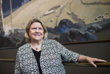 At the Smithsonian National Air and Space Museum, curator and chair of the Space History Department Valerie Neal '71 stands next to A Cosmic View, artist Robert McCall's 1976 mural celebrating space exploration. Photo by Lisa Helfert