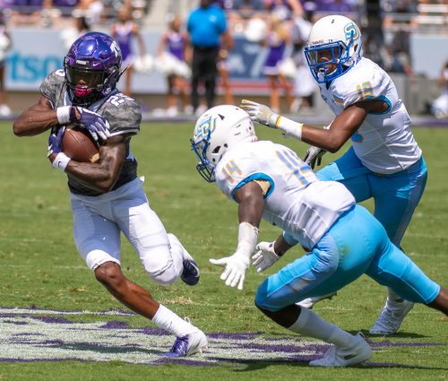 TCU football player KaVontae Turpin protects the football with both hands as two players from Southern chase the play.