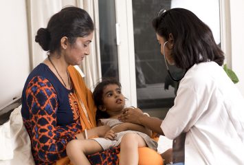 Mother with sick daughter being examined by doctor