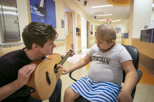 Dr. J Mack Slaughter makes music with Lilianna, 10, during a visit to Children's Medical Center in Dallas. Photo by Rodger Mallison