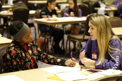 Eighth grader Jayla Perkins gets help on her essay from Alyssa Padilla as the Introduction to Women and Gender Studies class assisted Girl, Inc members. Photo by Ross Hailey