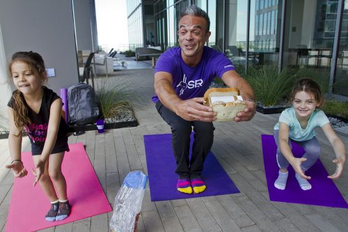 Poser Kids yoga leader Mateo Marquez makes a peanut butter sandwich as he shows sisters Scarlett, 5, and Zooey Horne, 7, a yoga pose. Photo by Mark Graham