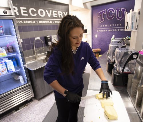 Brooke Helms, director of sports nutrition, works for several hours prior to the start time on game day to prepare snacks and hydration options for the players. Photo by Glen E. Ellman