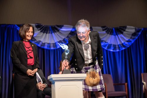 Provost emeritus R. Nowell Donovan symbolically passed the "torch of knowledge" to Teresa Abi-Nader Dahlberg at his retirement ceremony. Photo by Glen E. Ellman