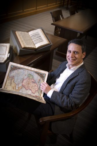 Alex Hidalgo, associate professor of history and director of undergraduate studies, reviews old maps in his favorite place on campus, the Special Collections reading room on the third floor of the Mary Couts Burnett Library. Photo by Joyce Marshall