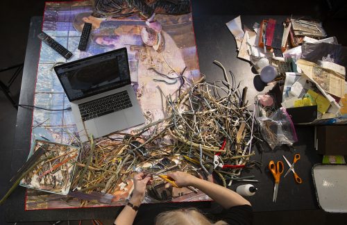 Overhead view of the hands of mixed media artist Mary McCleary '72 as she begins work on a collage. McCleary was named Texas 2-D Artist of the Year by the Texas Legislature in 2019. She is Regent's Professor of Art Emeritus at Stephen F. Austin State University in Nacogdoches, Texas where she taught from 1975-2005. Her collages made from found objects are sold through Moody Gallery in Houston. Photo by Rodger Mallison, December 16, 2019