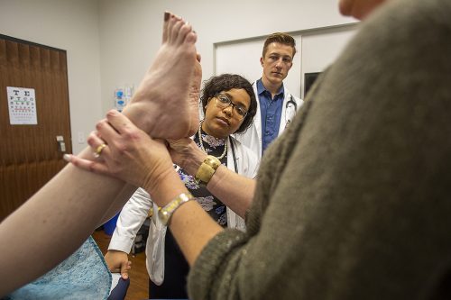 Medical students Charna Kinard and Jonas Kruse watch an examination of feet during a clinical skills session. 