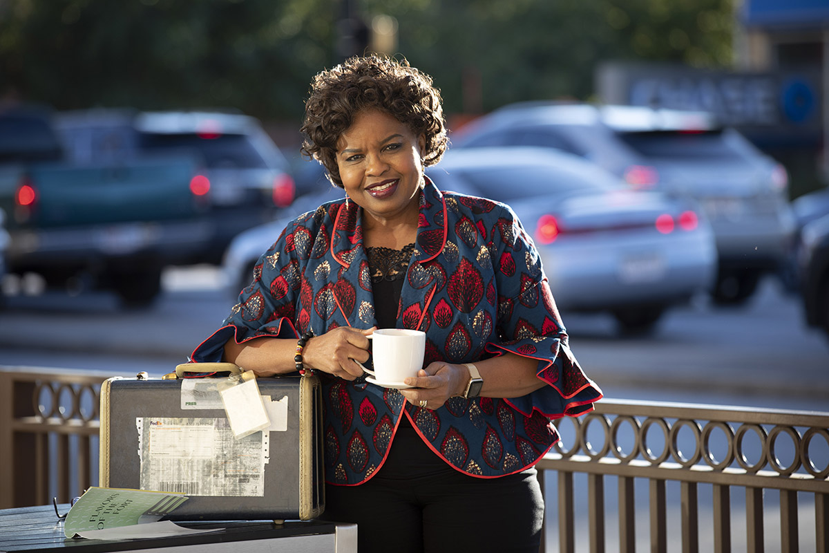 Dr. Amiso George, Associate Professor of Strategic Communication, is an expert in crisis communications in countries around the world. She is originally from Nigeria and has taught, researched and consulted on crisis communications for nearly 30 years. She poses between travels at Starbucks in the Campus Store with an old suitcase that symbolizes for her, travel and connecting with people from different cultures on Thursday, October 31, 2019. Photo by Joyce Marshall
