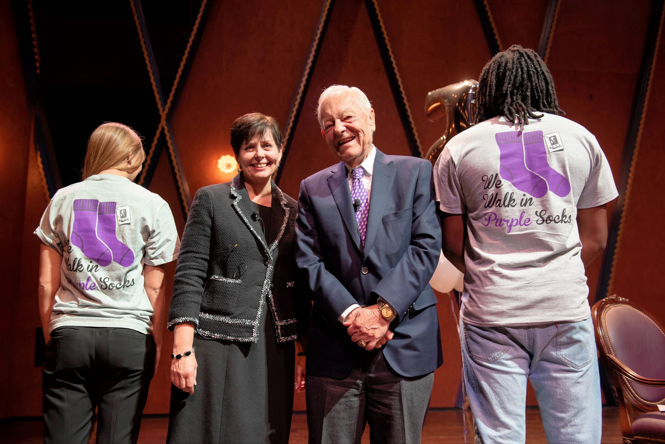 Dean Kristie Bunton and Bob Schieffer stand on stage at the PepsiCo Recital Hall in between Schieffer College students Abbey Widick and Brandon Kitchin as they model the 
