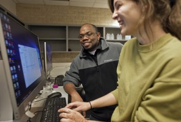 Omar Harvey and a female student talk in front of a computer.