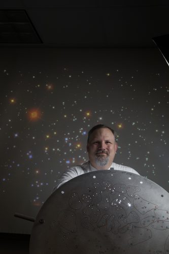 TCU Associate Professor of Physics and Astonomy Peter Frinchaboy poses with one of the Sloan Digital Sky Survey (SDSS) "plug plates", a specially prepared aluminum disc used for making spectrum measurements of stars and galaxies. Each plate is drilled with hundreds of tiny holes that map to a specific region of the sky. According to Dr. Frinchaboy, the holes are then "plugged with fiber optics to take the light from the telescope to the spectrographs. Each fiber hole gathers light from a specific star or galaxy. The holes need to be drilled to an accuracy of 9 microns to be able to get the most light into the 200 micron fiber optic. Each plug plate is approximately 3 degrees or 6 full moons in diameter on the sky. SDSS has drilled and observed over 11,000 plug plates as part of the survey over the last 22 years.” Photo by Rodger Mallison, September 28, 2020