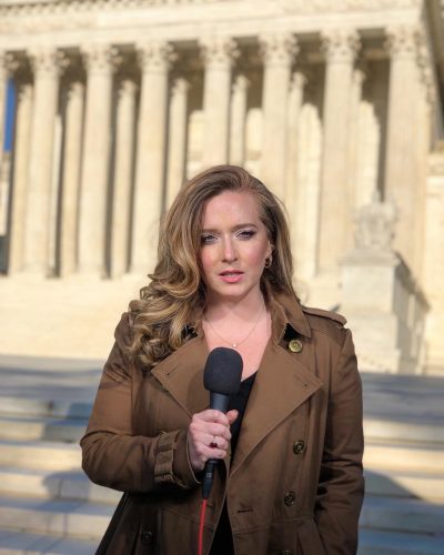 Christina Ruffini standing in front of the U.S. Capitol with a microphone in hand.