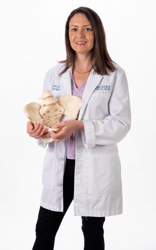 Portrait of April Bleich holding a model of a pelvis.