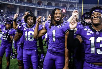 TCU Football players in uniform face the crowd with hands forming the "frog sign." Photo by Ellman Photography