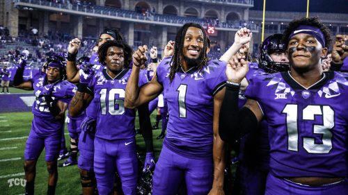 TCU Football players in uniform face the crowd with hands forming the "frog sign." Photo by Ellman Photography