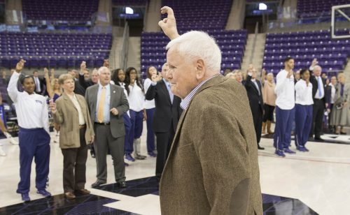 Ed Schollmaier salutes others with the Horned Frog hand sign.