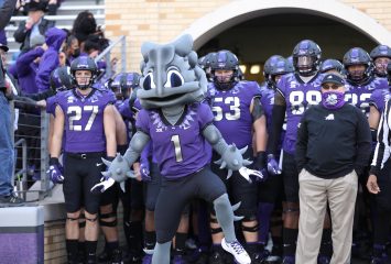 The TCU Football team, coach and mascot get ready to run onto the field for a football game.