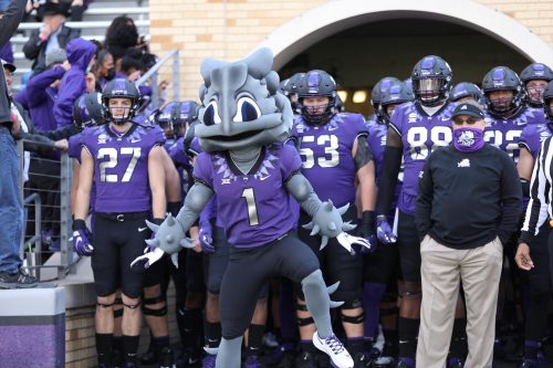 The TCU Football team, coach and mascot get ready to run onto the field for a football game.