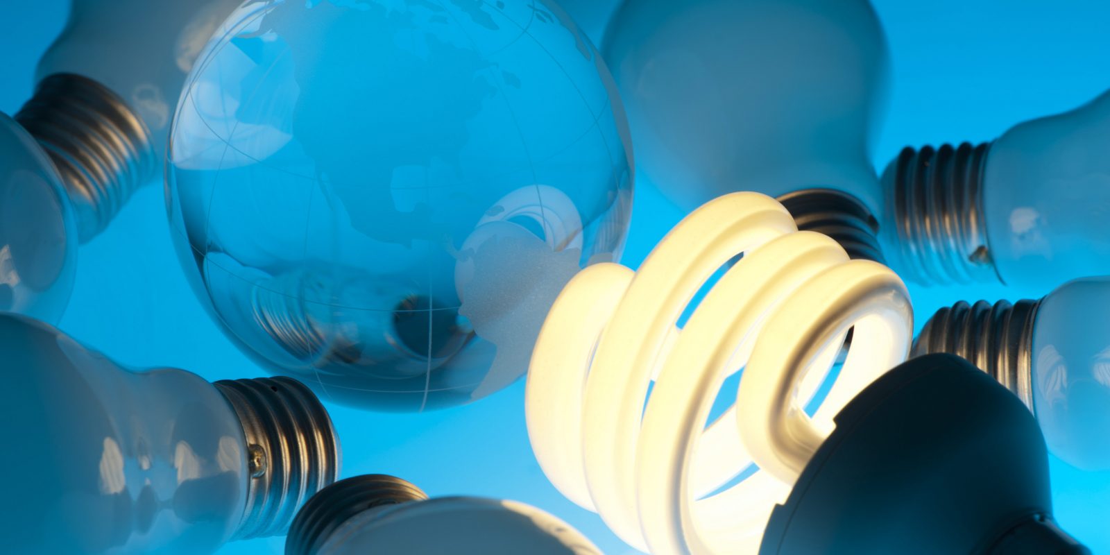 Lit Energy efficient light bulb in a group of old light bulbs with earth globe