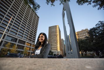 Yashoda Bhagwat, associate professor of marketing, has researched the cost of corporate sociopolitical activism. She is photographed in downtown Fort Worth in Burnett Park with the sculpture “Man with a Briefcase” by Jonathan Borofsky.