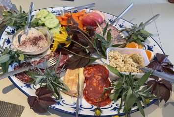 A charcuterie board with various cheeses, sliced meats, couscous
