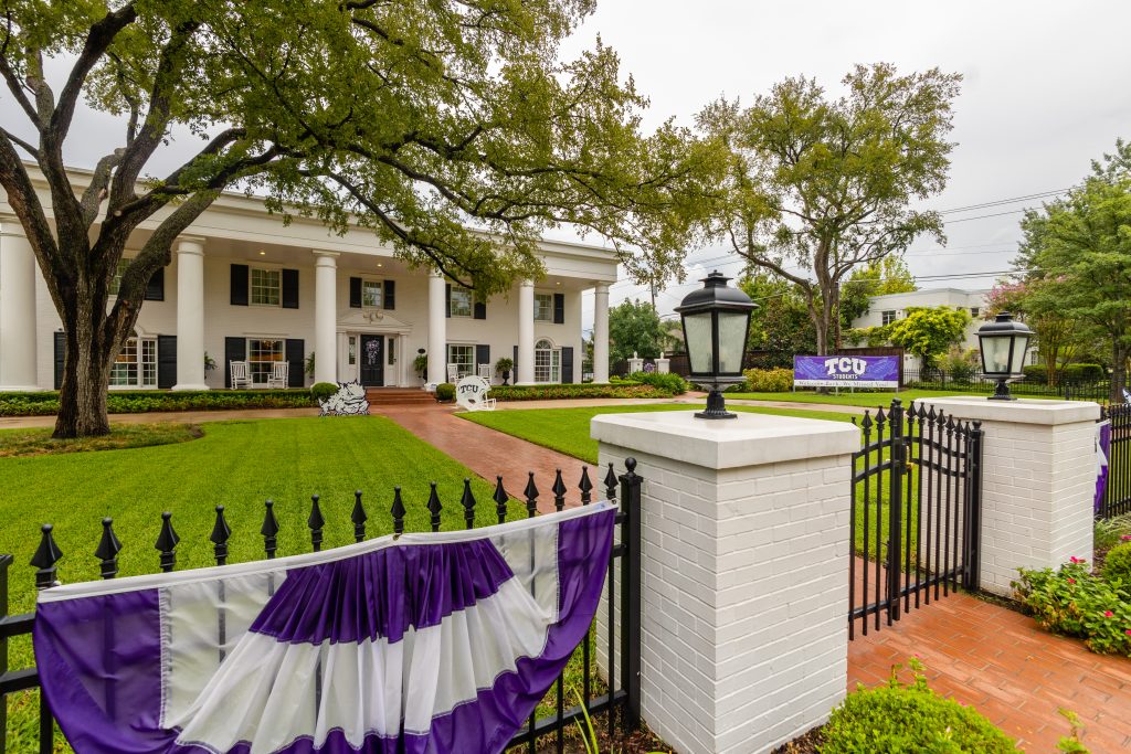 A white house near campus with decorative purple and white banners, welcoming students back to campus.