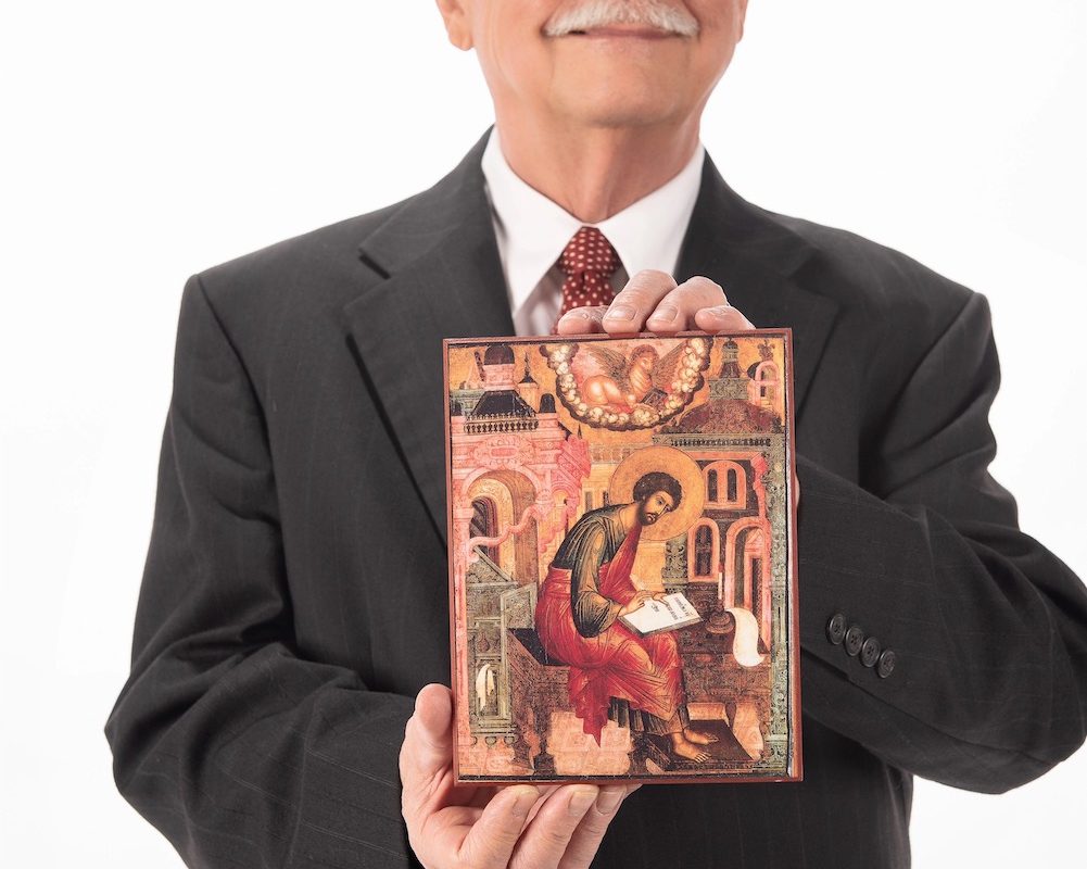 A suited Moessner presents a decorative bible cover.