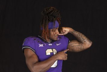 TCU wide receiver Savion Williams, wearing a purple Horned Frogs football jersey, flexes his left bicep as he points to it with his right index finger.