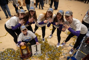 Coach Karen Monez (kneeling), and from left to right, Mikole Hogan, Jeanne Haverhill, Katie Zaun, Stephanie Allan and Stephanie Grundsøe, pose with the NCAA national championship trophy at WVU Coliseum in Morgantown, West Virginia, on March 9, 2024.