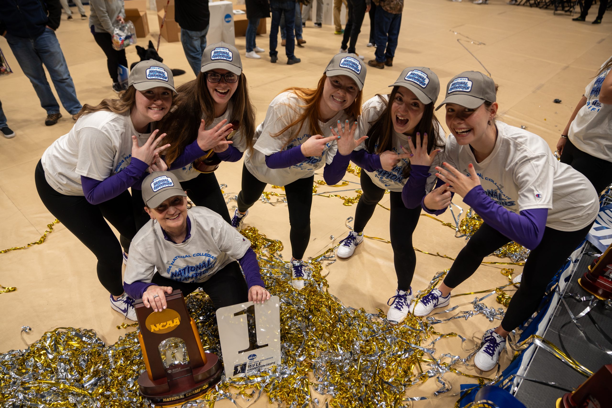 Coach Karen Monez (kneeling), and from left to right, Mikole Hogan, Jeanne Haverhill, Katie Zaun, Stephanie Allan and Stephanie Grundsøe, pose with the NCAA national championship trophy at WVU Coliseum in Morgantown, West Virginia, on March 9, 2024.