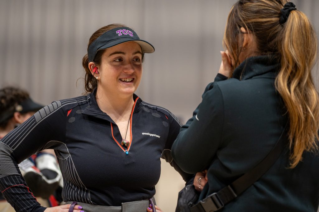 Stephanie Allan, in conversation and standing with hands on her hips, photographed during the 2024 NCAA Rifle Championships in Morgantown, West Virginia.