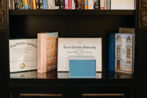 A photograph of a TCU undergraduate diploma sitting on a bookshelf in Dr. Richard Georges' office in the main building of H. Lavity Stoutt Community College.