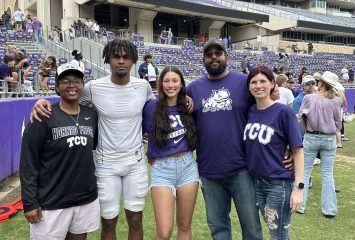 Eric McAlister photographed alongside his family on the field of Amon G. Carter Stadium. McAlister is dressed in his white football pants, a white top and white cleats, and his family members are all wearing TCU gear.