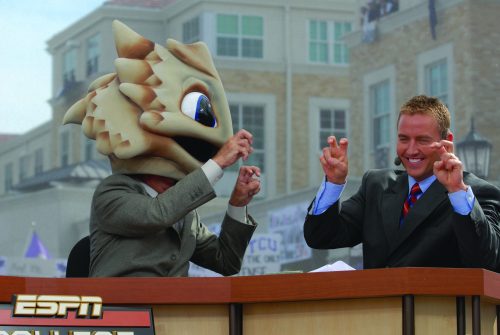 Photograph of Kirk Herbstreit and Lee Corso on the set of ESPN's when the show visited TCU's campus in November 2009. Both Herbstreit and Corso are holding up the TCU hand sign. Corso wears the SuperFrog head to signify his prediction that TCU would win the game against Utah.