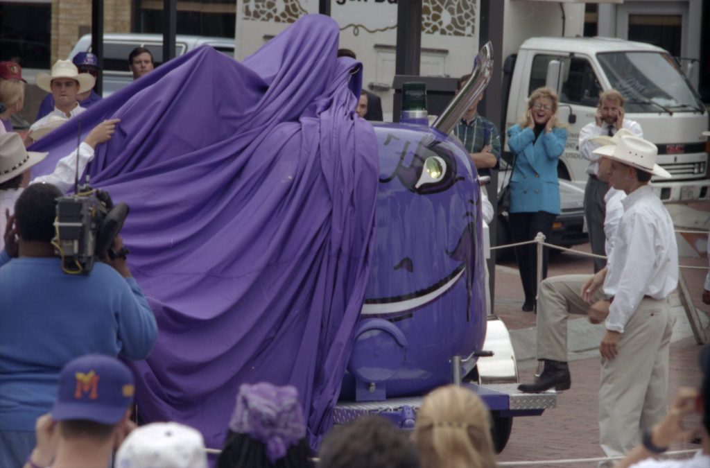 The TCU Frog Horn is uncloaked from beneath a purple sheet. Multiple onlookers cover their ears in preparation for the horn's long-awaited debut.