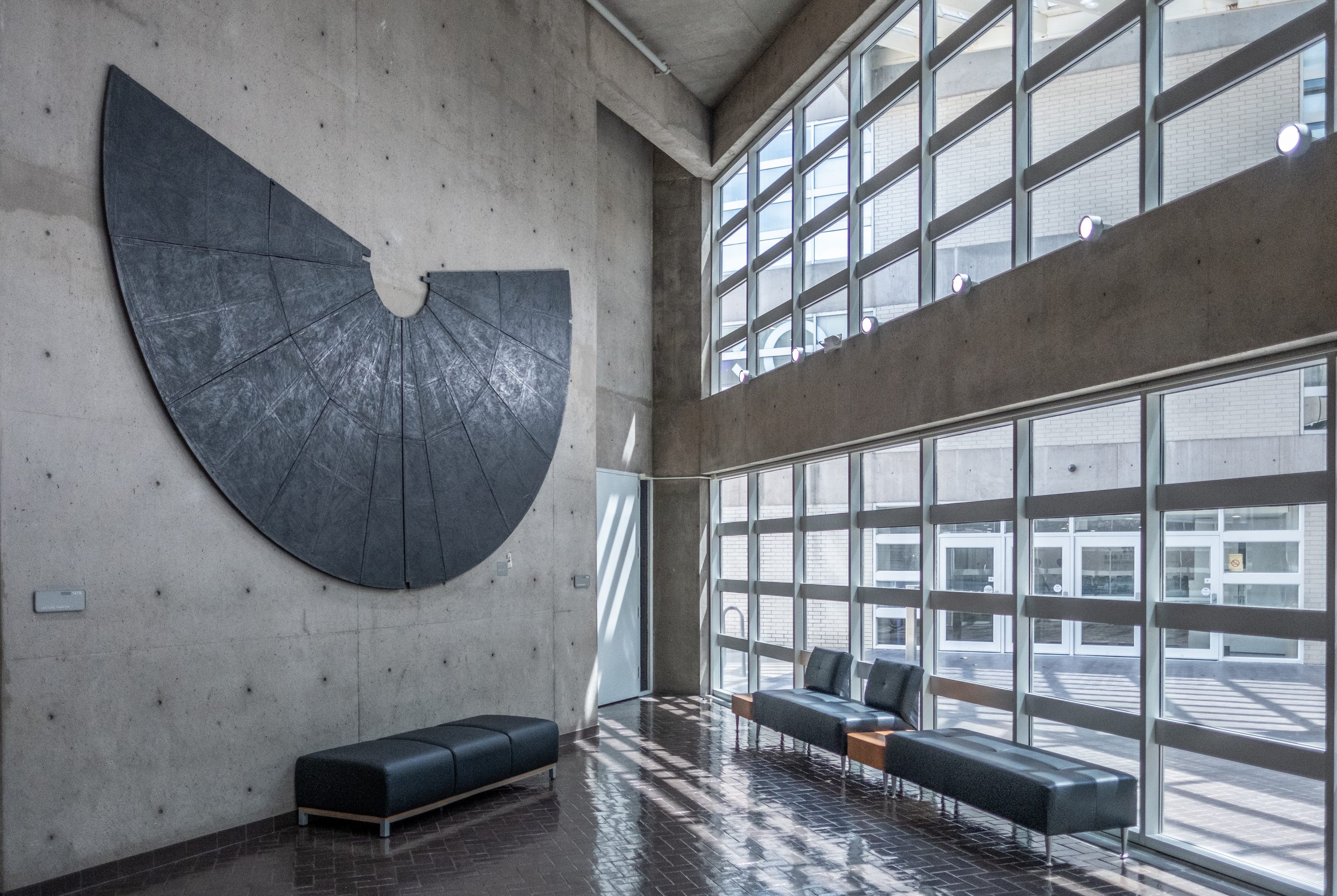 A photograph showing Joe Guy's 1982 work, "Echo," on display in Moudy North. The 10 x 16-foot dark grey structure is made of wood, paper and graphite. It "both attracts and reflects light," according to a press release from the Dallas Museum of Art.