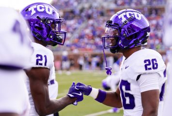 Photograph of TCU student-athletes Bud Clark and Jeremy Payne sharing a handshake during the Horned Frogs' Sept. 21 road football game at SMU. Clark and Payne wear TCU's white road football uniforms and purple helmets.
