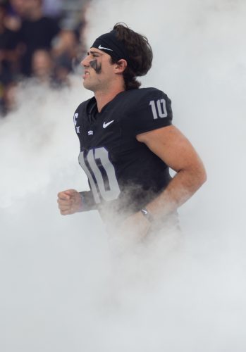 Josh Hoover, wearing a black TCU football jersey embroidered with the number 10 in silver, emerges from the fog of the Horned Frogs tunnel ahead of TCU's Sept. 14 game against UCF. Hoover jogs onto the field moments ahead of kickoff.