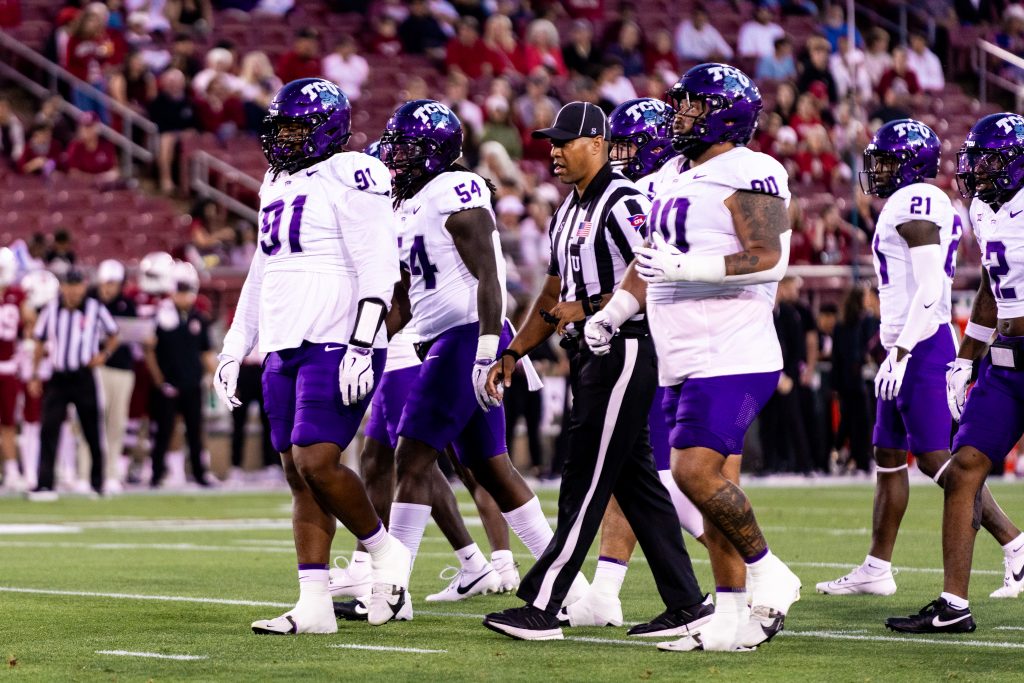 Photograph showing members of the TCU Horned Frogs defense standing on the field at Stanford Stadium during a night game against the Cardinal in late-August, 2024.