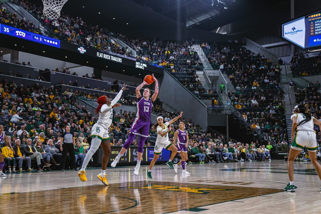 Photograph of Sedona Prince taking a fadeaway jump shot during a women’s college basketball game at Baylor University's Foster Pavilion, with spectators visible in the background.