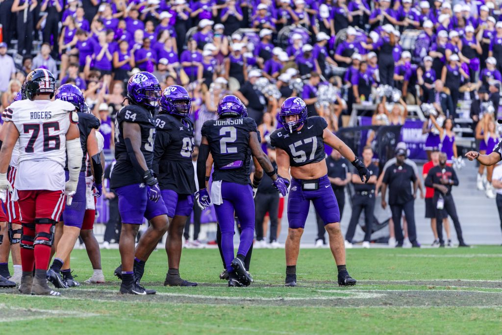 Photograph of TCU Horned Frogs defenders standing on a field during an October, 2024 football game against the Texas Tech Red Raiders. 