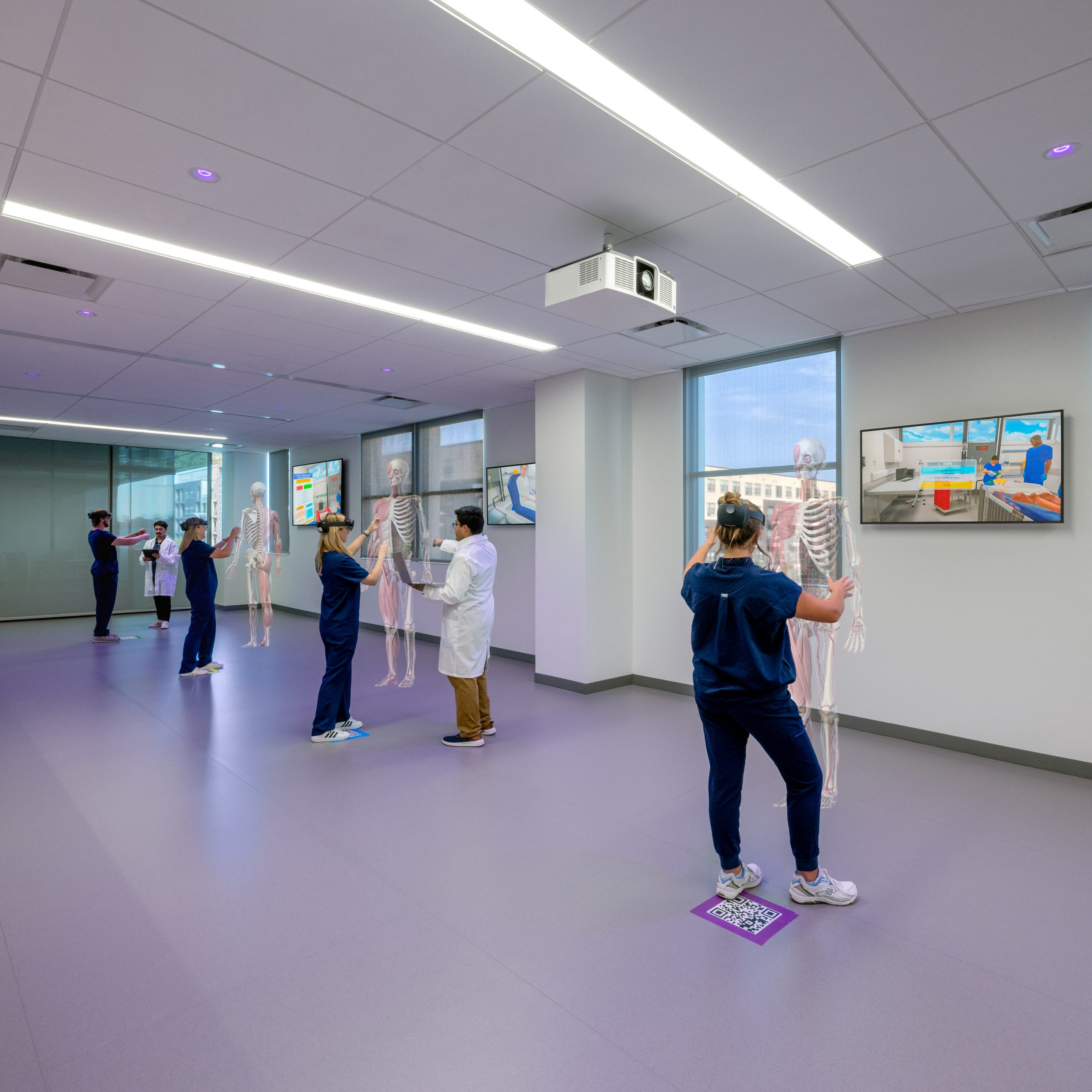 Photo of medical students standing in a spacious, well-lit room, engaging with advanced educational technology for hands-on learning.