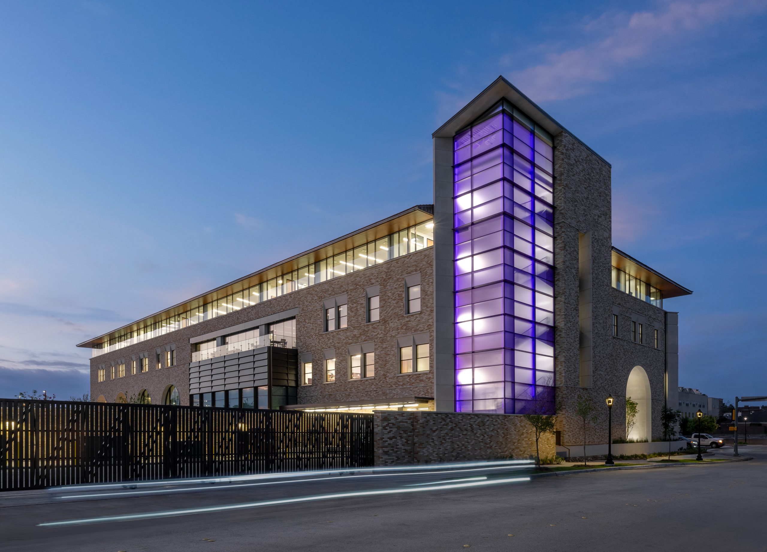 Street-level view of a purple-lit staircase at Arnold Hall, home of the Burnett School of Medicine, photographed in early morning or dusk.