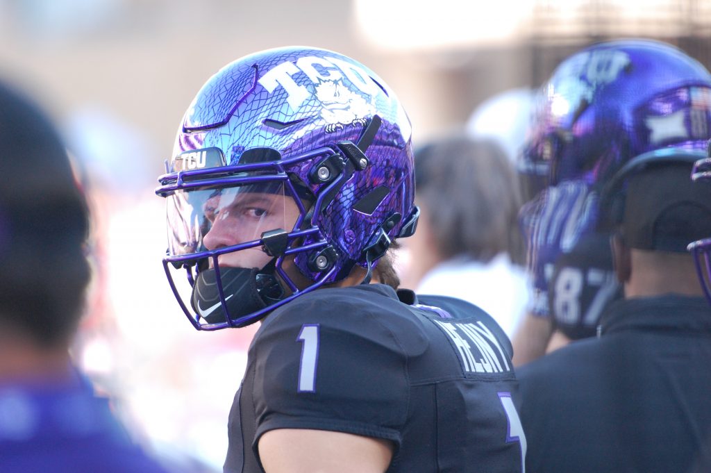 Photograph of TCU quarterback Hauss Hejny wearing a purple Horned Frogs football helmet and black jersey during an October 2024 college football game against the Texas Tech Red Raiders in Fort Worth, Texas. Hejny looks toward his left as he stands on the sidelines.