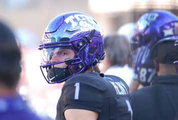 Photograph of TCU quarterback Hauss Hejny wearing a purple Horned Frogs football helmet and black jersey during an October 2024 college football game against the Texas Tech Red Raiders in Fort Worth, Texas. Hejny looks toward his left as he stands on the sidelines.