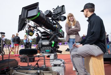 Photograph of a camera person and another individual having a conversation at TCU’s Lowdon Track and Field Complex.