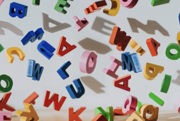 Stock image of multi-colored letter blocks scattered against a light gray background.